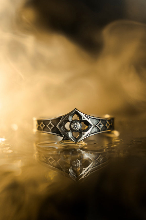A professional studio photograph of a matching two-piece sterling silver wedding ring set. Both rings feature a prominent, raised Greek-style cross motif in the center, which holds a round, bezel-set white crystal. The interior of the cross arms has a fine, cross-hatched grid texture. Along the sides of the high-polished silver bands are recessed, four-lobed quatrefoil shapes. The rings are presented against a pitch-black background, making the p __etsy:8051335185