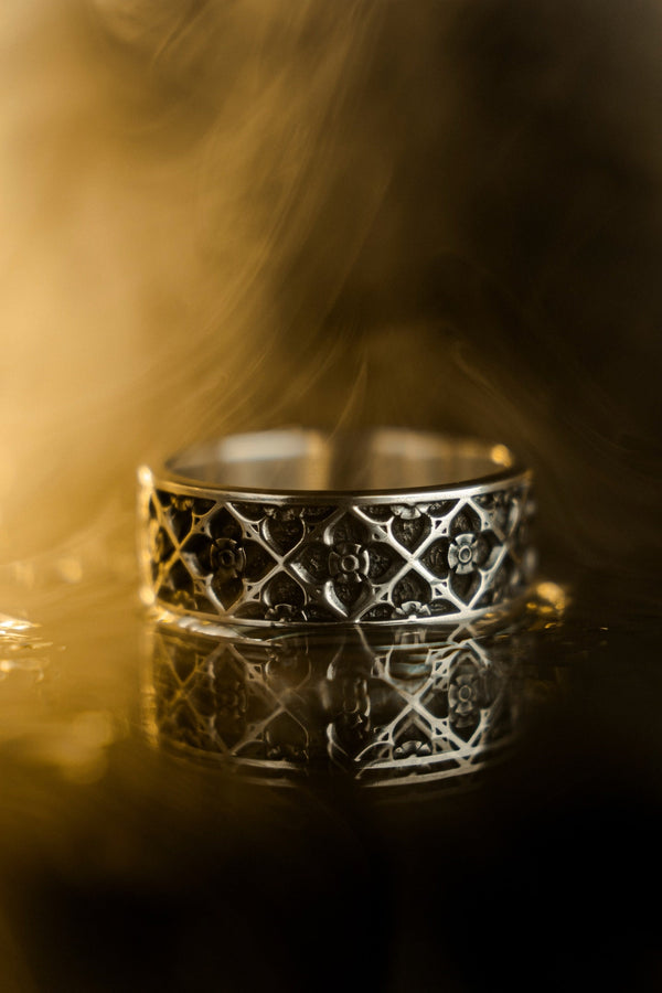 A professional studio photograph of a matching two-piece sterling silver wedding ring set. Both rings feature a prominent, raised Greek-style cross motif in the center, which holds a round, bezel-set white crystal. The interior of the cross arms has a fine, cross-hatched grid texture. Along the sides of the high-polished silver bands are recessed, four-lobed quatrefoil shapes. The rings are presented against a pitch-black background, making the p __etsy:8051335185