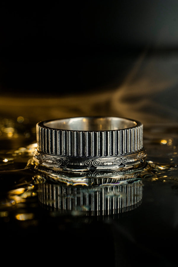 A polished sterling silver wedding band inspired by historical Greek architecture, featuring full-length vertical column lines and detailed Ionic scrollwork. The ring’s reflective interior contrasts with the textured exterior, emphasizing craftsmanship and depth. This Art Deco–style temple band is ideal for those who love structural jewelry rooted in ancient culture and timeless design. (etsy image id: 7193919287)