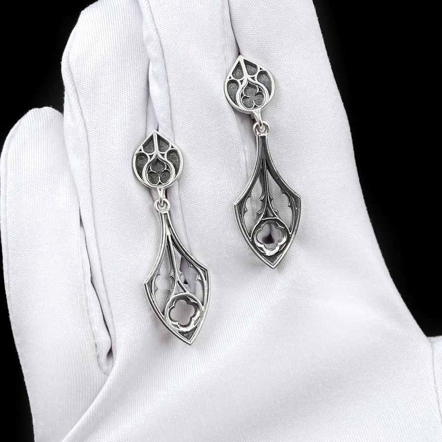 Embrace the dark appeal of gothic fashion with our Sterling Gothic Earrings. Each pair is exquisitely crafted in a gothic style, bringing a touch of mystery and romance to your look. An ideal choice for those who appreciate dark shades of elegance. The image highlights the high-contrast finish of the 925 sterling silver. The "relief" casting gives the tracery lines a three-dimensional quality, mimicking carved stone. (etsy image id: 6150699379)