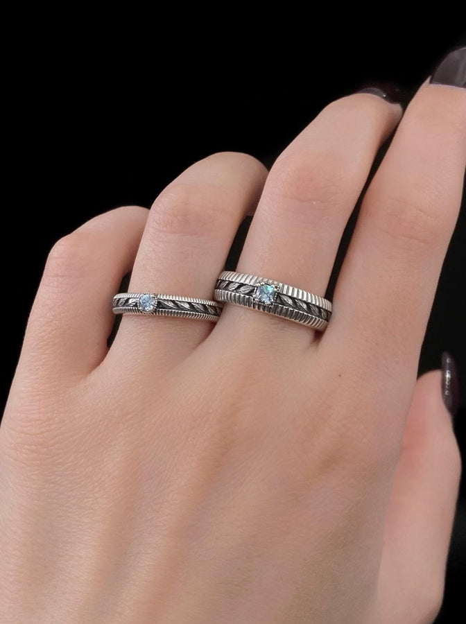 A nature-inspired silver wedding ring featuring raised leaf motifs and a shimmering round gemstone set in the center. The Art Nouveau style is expressed through smooth curves and organic detailing along the band. Ideal for brides or grooms who appreciate delicate plant symbolism, handcrafted jewelry, and an elegant blend of vintage and contemporary design elements in their wedding set. (etsy image id: 6300134508)