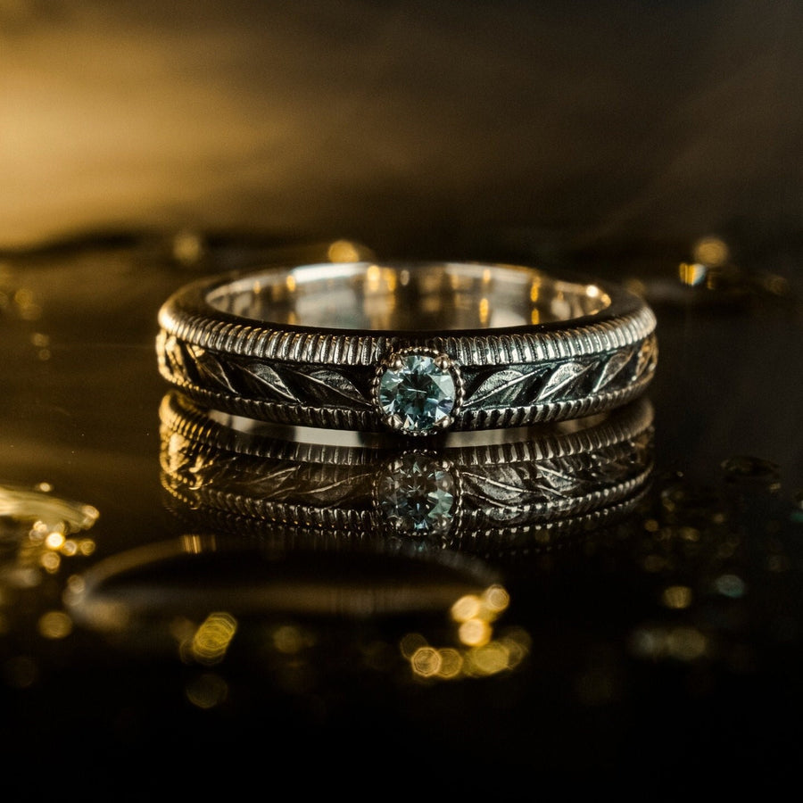 A nature-inspired silver wedding ring featuring raised leaf motifs and a shimmering round gemstone set in the center. The Art Nouveau style is expressed through smooth curves and organic detailing along the band. Ideal for brides or grooms who appreciate delicate plant symbolism, handcrafted jewelry, and an elegant blend of vintage and contemporary design elements in their wedding set. (etsy image id: 6300134508)