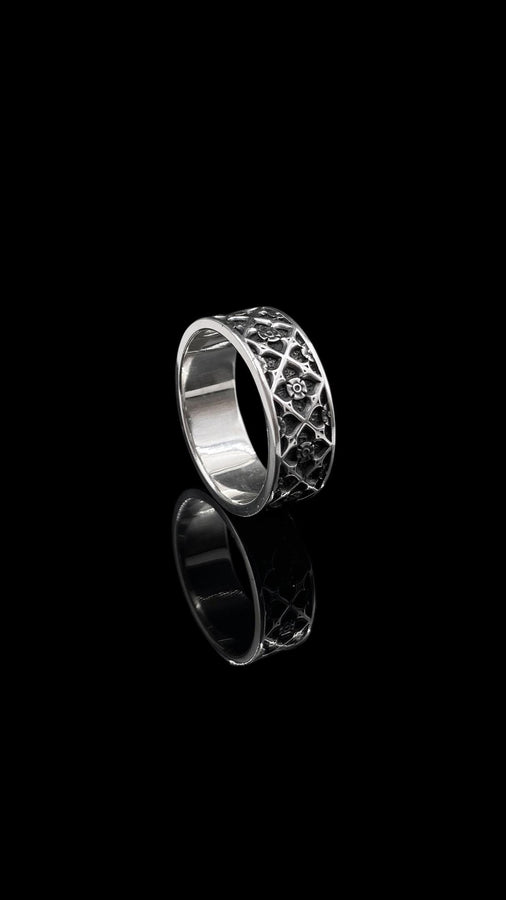 A professional studio photograph of a matching two-piece sterling silver wedding ring set. Both rings feature a prominent, raised Greek-style cross motif in the center, which holds a round, bezel-set white crystal. The interior of the cross arms has a fine, cross-hatched grid texture. Along the sides of the high-polished silver bands are recessed, four-lobed quatrefoil shapes. The rings are presented against a pitch-black background, making the p __etsy:8051335185