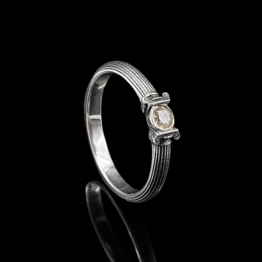 The photograph captures a slim Victorian silver ring with a gemstone framed by sculpted column motifs. Fine linear textures cover the band, giving it a classical, antique appeal. The gemstone sparkles softly, contrasting the darker oxidized grooves. This intricate design suits those who appreciate architectural jewelry, artistic detailing, and meaningful handmade engagement pieces. (etsy image id: 6976743880)
