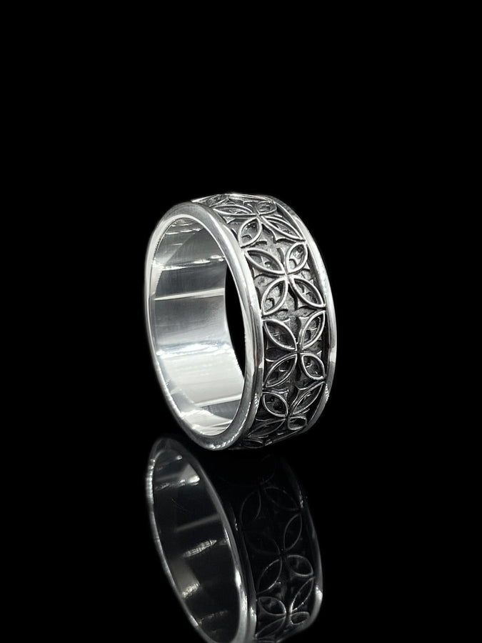 A professional studio photograph of a matching two-piece sterling silver wedding ring set. Both rings feature a prominent, raised Greek-style cross motif in the center, which holds a round, bezel-set white crystal. The interior of the cross arms has a fine, cross-hatched grid texture. Along the sides of the high-polished silver bands are recessed, four-lobed quatrefoil shapes. The rings are presented against a pitch-black background, making the p __etsy:8051335185