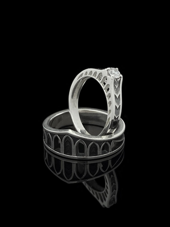 A professional studio photograph of a matching two-piece sterling silver wedding ring set. Both rings feature a prominent, raised Greek-style cross motif in the center, which holds a round, bezel-set white crystal. The interior of the cross arms has a fine, cross-hatched grid texture. Along the sides of the high-polished silver bands are recessed, four-lobed quatrefoil shapes. The rings are presented against a pitch-black background, making the p __etsy:8051335185