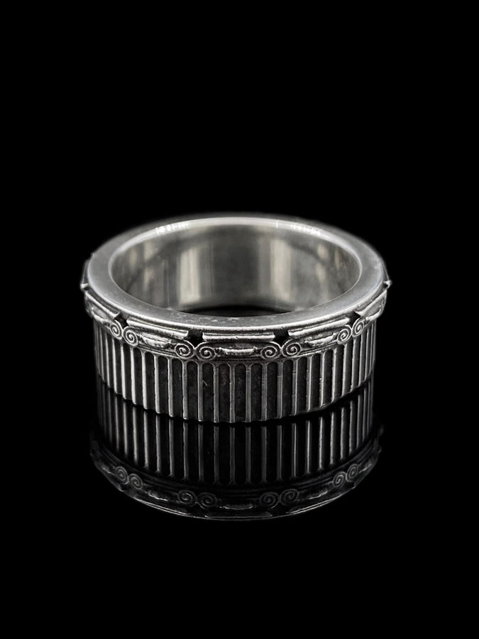 A polished sterling silver wedding band inspired by historical Greek architecture, featuring full-length vertical column lines and detailed Ionic scrollwork. The ring’s reflective interior contrasts with the textured exterior, emphasizing craftsmanship and depth. This Art Deco–style temple band is ideal for those who love structural jewelry rooted in ancient culture and timeless design. (etsy image id: 7193919287)