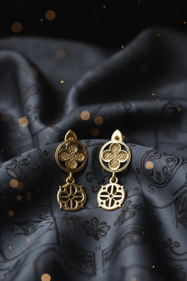The image highlights the specific textures of the casting. The top stud has a "waffle" or lattice texture inside the quatrefoil lobes, mimicking chainmail or stone carving. The bottom drop is smooth and open, providing a visual counterweight. The 925 sterling silver is treated with an antique patina to enhance the "old world" feel. Modeled as a versatile daily earring, the "coin" size is modest enough for office wear (etsy image id: 5775868859)
