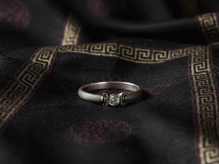 This image shows a Victorian-inspired sterling silver engagement ring featuring an elegant architectural design with slender vertical grooves resembling ancient columns. A small gemstone sits securely in a sculpted capital-like setting, giving the piece a refined antique feel. The ring appears polished, delicate, and artistic, ideal for lovers of classical or historical jewelry. (etsy image id: 7417879124)