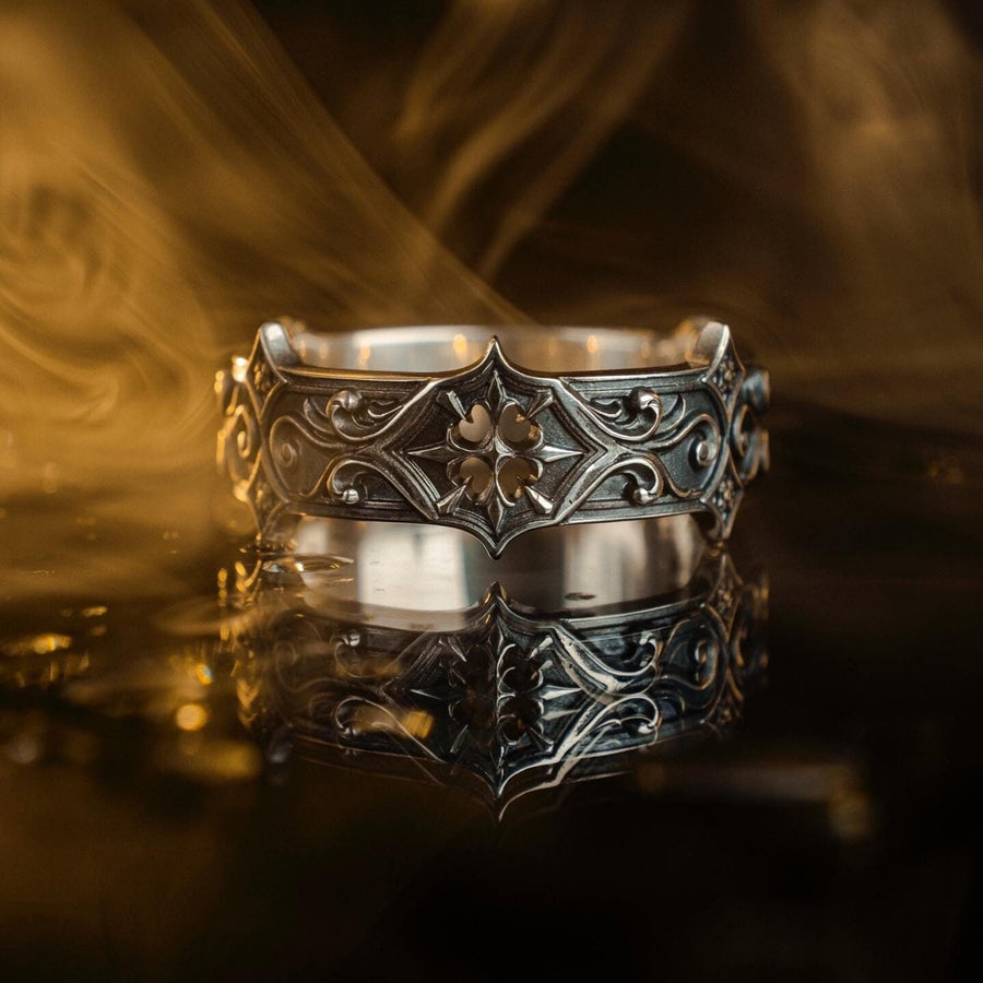 Handmade sterling silver band with an intricate gothic crown motif in the center, framed by swirling ornamental engravings. The deep relief and antique darkened finish evoke historic cathedral carvings. Ideal for customers seeking dark romantic jewelry, gothic accessories, medieval wedding rings, and meaningful silver bands with symbolic architecture-inspired designs. (etsy image id: 7423455351)