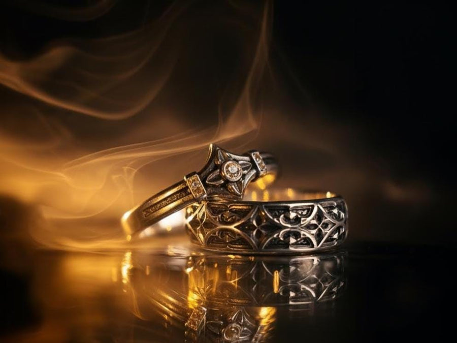 A high-resolution macro photograph of a matching sterling silver gothic wedding ring set resting on softly draped, luxurious white satin. The set features a wider masculine band and a slightly narrower feminine band. Both rings display a continuous engraved arcade of pointed medieval arches along the bottom edge, centering on a polished geometric rhombus frame that holds a brilliant round white gemstone. The polished silver beautifully contrasts  (etsy image id: 7928017042)