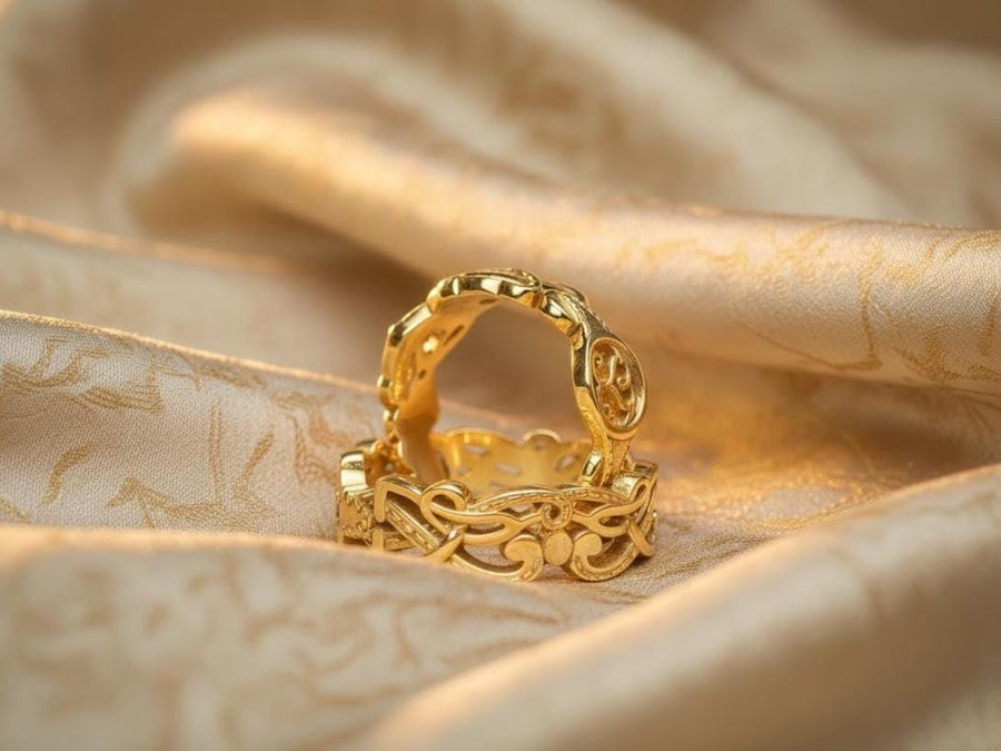 A studio shot of a matching two-piece sterling silver ring set on a black reflective surface. The standing ring is a signet style featuring an oval face with a raised Triskelion (triple spiral) motif. The ring lying flat is a wide band with an "openwork" or cut-out Celtic knot pattern. The silver is highly polished on the raised surfaces, contrasting with the dark shadows of the open areas.