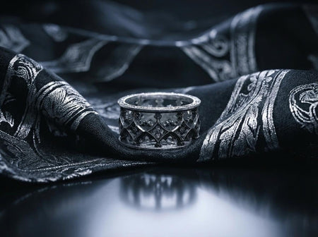 A detailed studio shot of a wide sterling silver ring with a "cut-out" or openwork design. The pattern consists of repeating, intersecting arches (ogee curves) that form a net-like lattice around the finger. The top and bottom edges are defined by solid, polished rails. The interior of the metal lattice is darkened with oxidation, contrasting with the bright outer surface. (etsy image id: 7452022894)