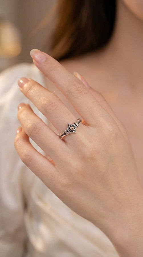 A high-resolution macro photograph of a matching sterling silver gothic wedding ring set resting on softly draped, luxurious white satin. The set features a wider masculine band and a slightly narrower feminine band. Both rings display a continuous engraved arcade of pointed medieval arches along the bottom edge, centering on a polished geometric rhombus frame that holds a brilliant round white gemstone. The polished silver beautifully contrasts  (etsy image id: 7928017042)