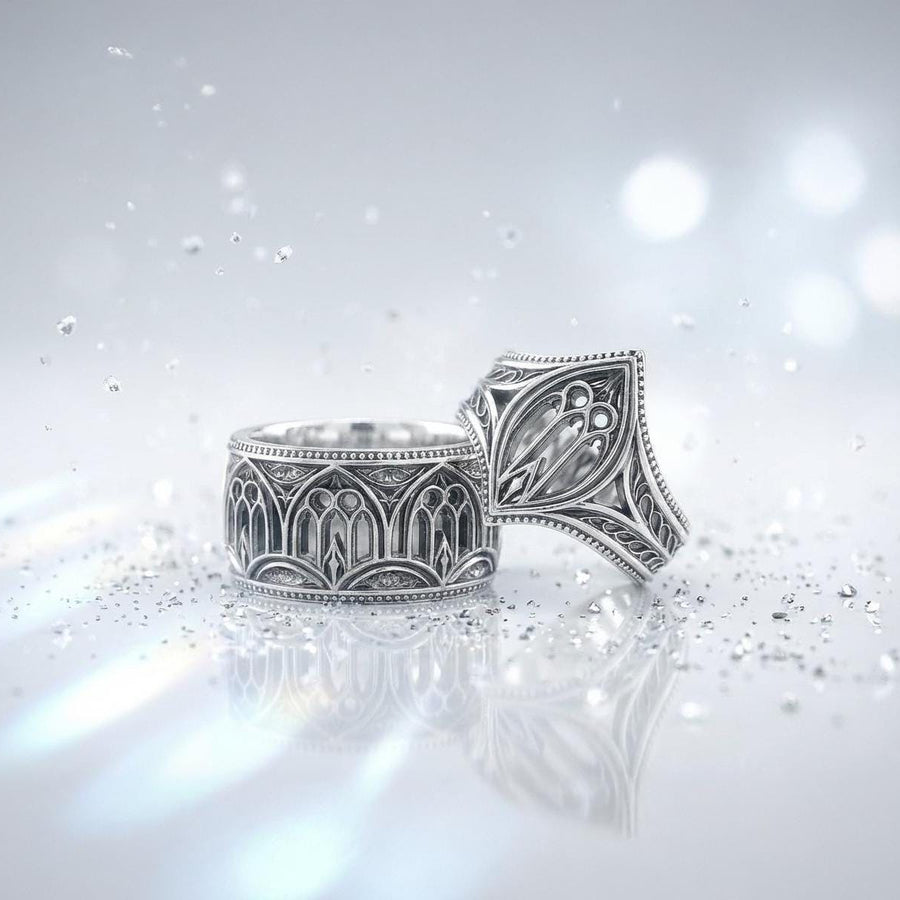 A high-resolution macro shot of a wide sterling silver wedding band resting on a sparkling, icy white surface. The ring features an intricate openwork design mimicking a Gothic cathedral window, complete with pointed lancet arches and delicate stone tracery. The polished silver highlights contrast beautifully against the dark, oxidized background, emphasizing the architectural depth of the piece.